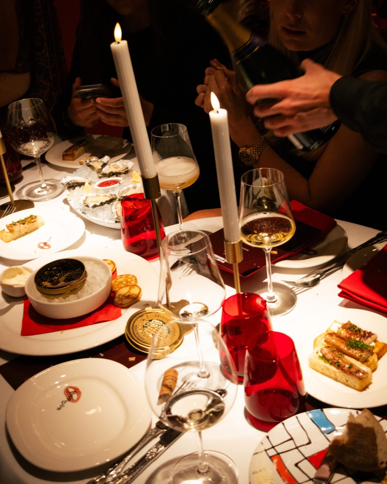 A candlelit table with red napkins in the interior of BISOUS in De Pijp