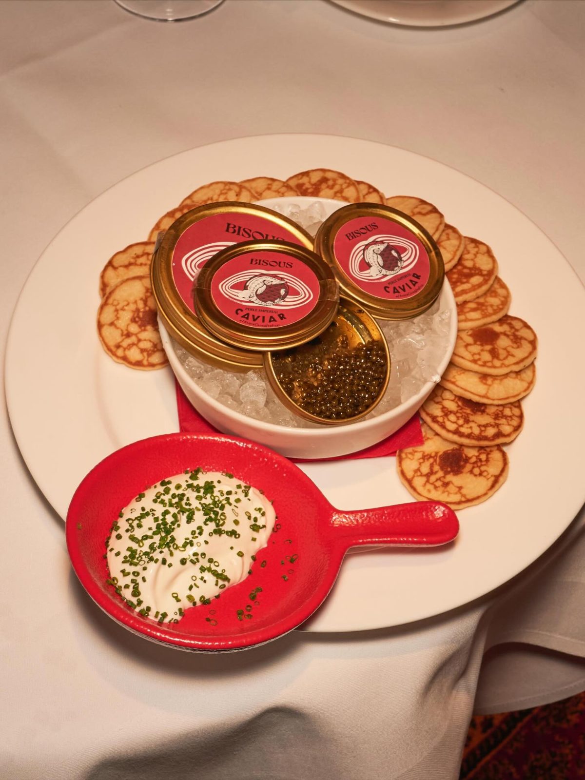 Tins of BISOUS Perle Imperial caviar on ice, with blinis and chive crème fraîche at BISOUS in Amsterdam