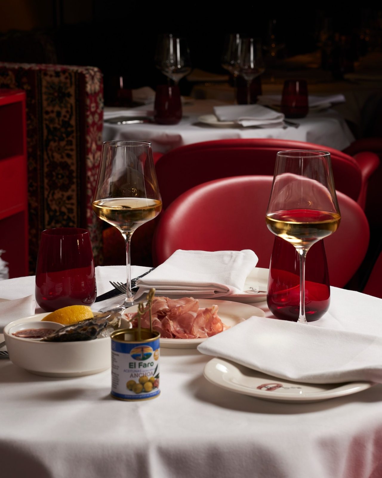 Wine glasses and small dishes on a set table in the red interior of BISOUS